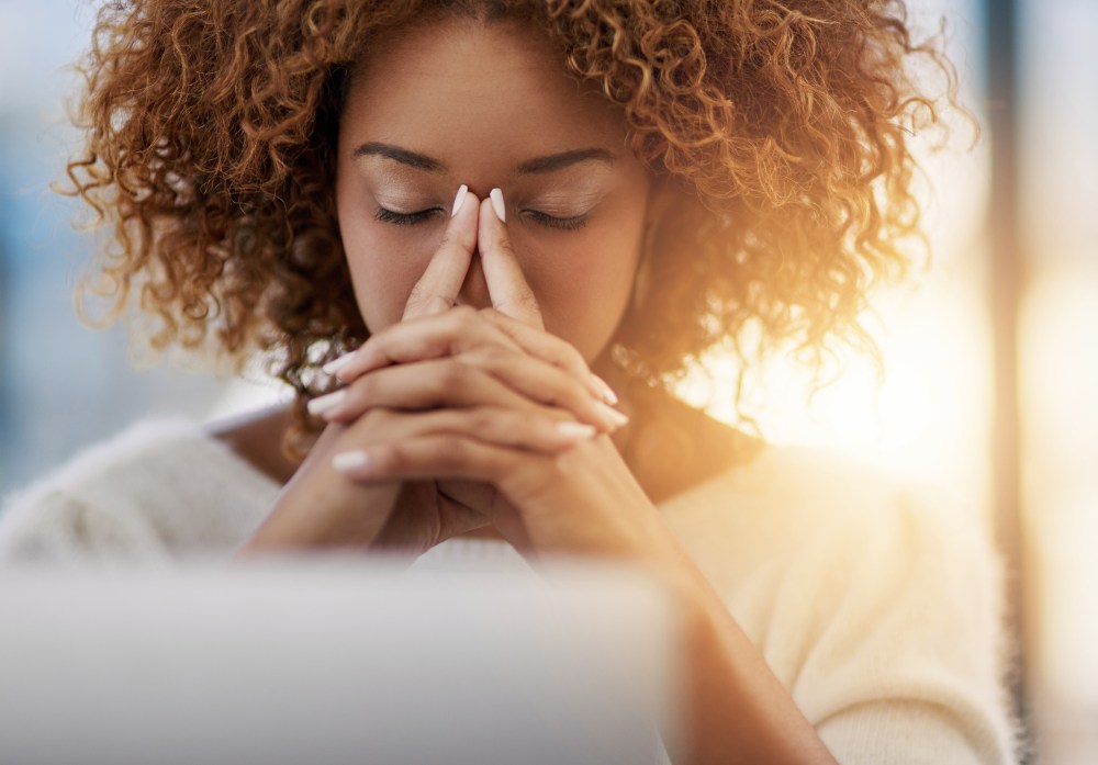 Image: A woman sits at her desk with eyes closed