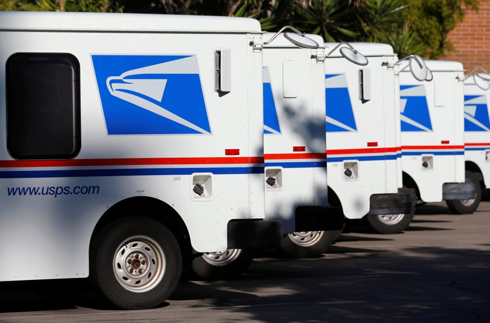 Image: U.S. postal service trucks sit parked at the post office in Del Mar, California