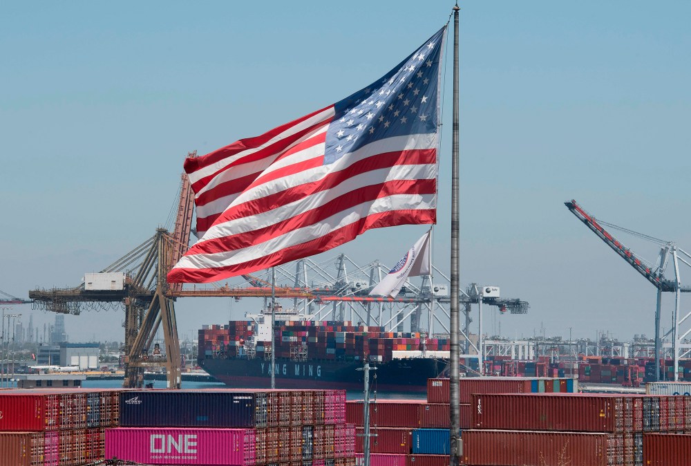 Image: The U.S. flag flies over a container ship unloading it's cargo from Asia, at the Port of Long Beach, California