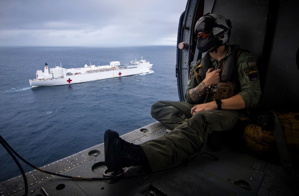 Image: A Naval aircrewman flies in a Seahawk helicopter alongside the USNS Comfort, a hospital ship, in the Pacific Ocean on on June 24, 2019.