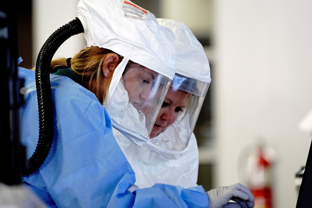 Image: Healthcare workers wearing powered air purifying respirator (PAPR) hoods process COVID-19 test samples at a drive-thru testing site operated by Avera Health inside the former Silverstar Car Wash, Sioux Falls