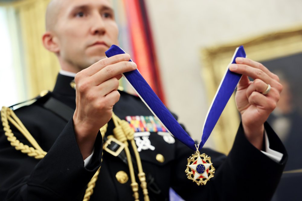 Image: A U.S. Marine military aide holds the Presidential Medal of Freedom for Trump to award to Holtz in the Oval Office at the White House in Washington