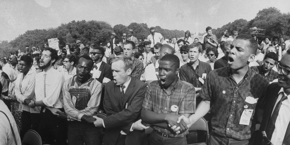 Image: Group of people holding hands during a civil rights rally in front of the Washington Monument.