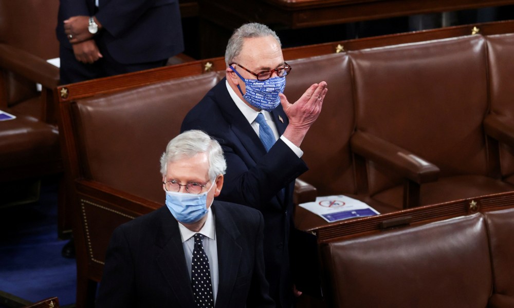 Image: Mitch McConnell faces left and Chuck Schumer behind him faces forward.