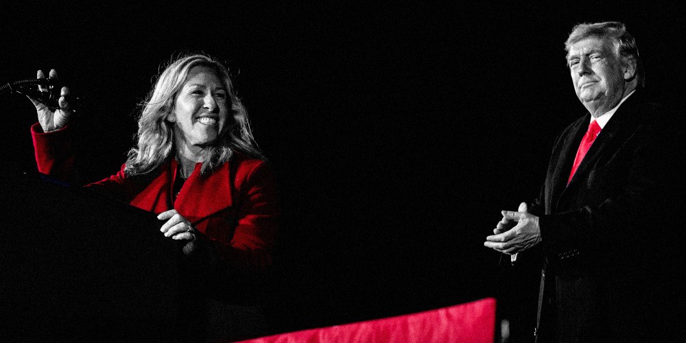 Image: Marjorie Taylor Greene speaks on stage and Donald Trump applauds in the background.