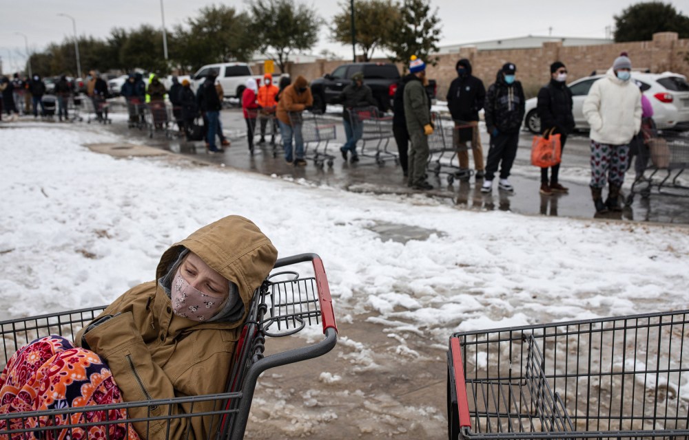 Image: A girl sits in a shopping cart waiting in a long line to enter a grocery store in Austin, Texas.
