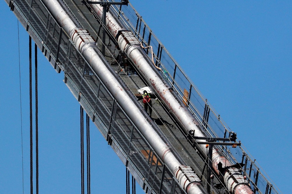 Image: A construction worker scales the northeast cables of the George Washington Bridge duering reconstruction in New York
