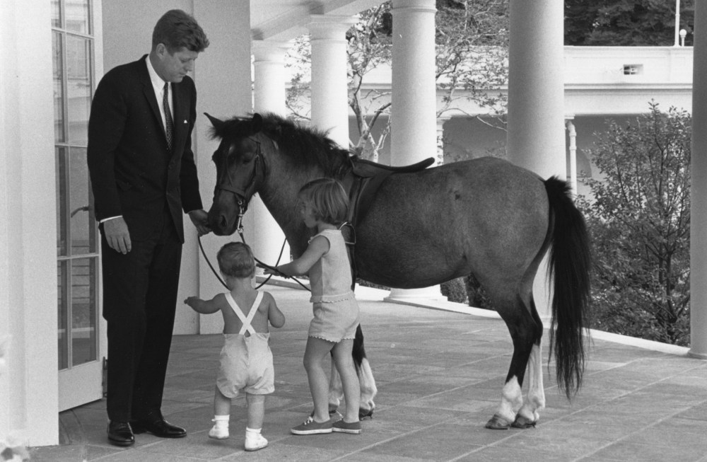 Image; Outside of the Oval Office, President John F. Kennedy and his children, John and Caroline, play with their pet pony, Macaroni, in 1962.