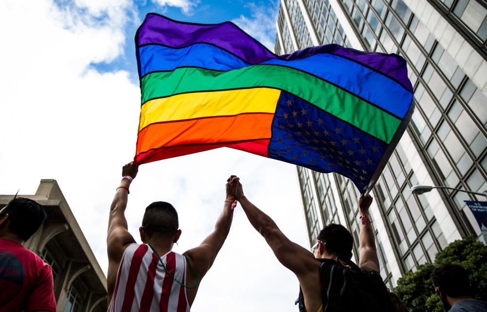 Image: A couple hold up a gay pride flag.