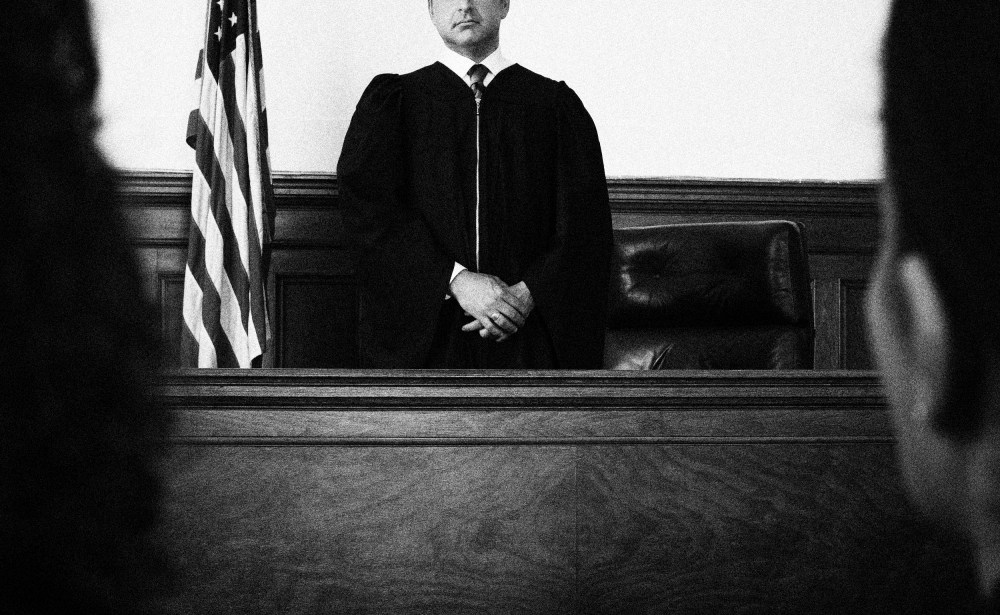 Image: Judge standing in front of defendants and lawyers