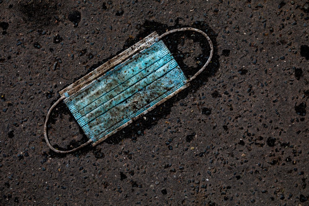 IMage: A discarded surgical mask on an asphalt street.