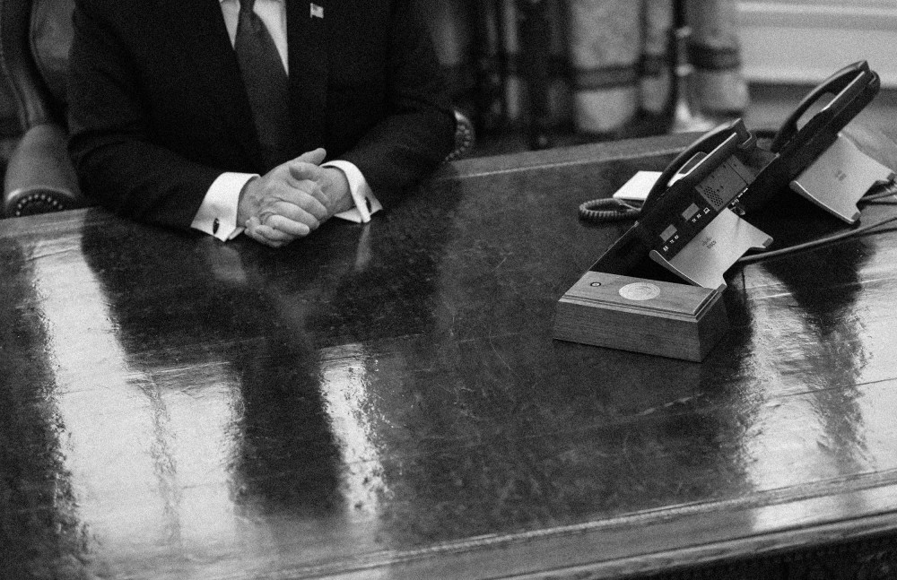 Image: Then-President Donald Trump is reflected on the Resolute Desk in the Oval Office at the White House in 2019.