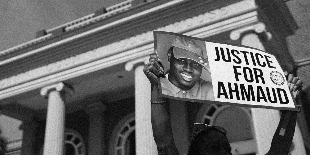 Image: A demonstrator holding a sign that reads, "Justice for Ahmaud"outside a courthouse.
