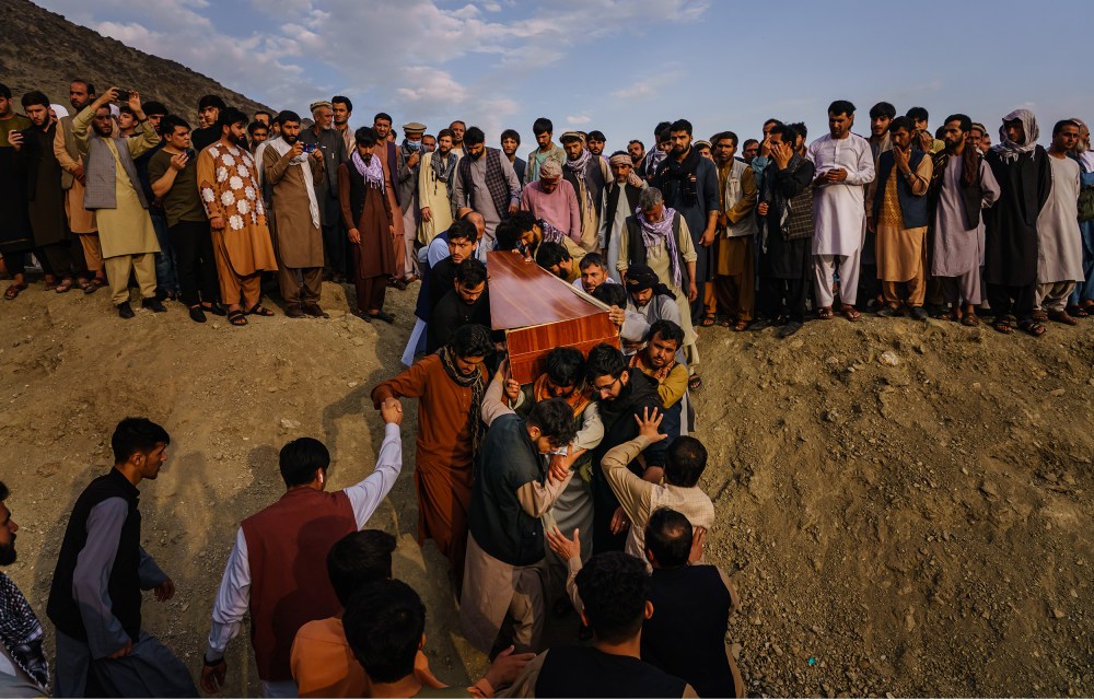 Image: Caskets being carried towards a gravesite at a mass funeral.