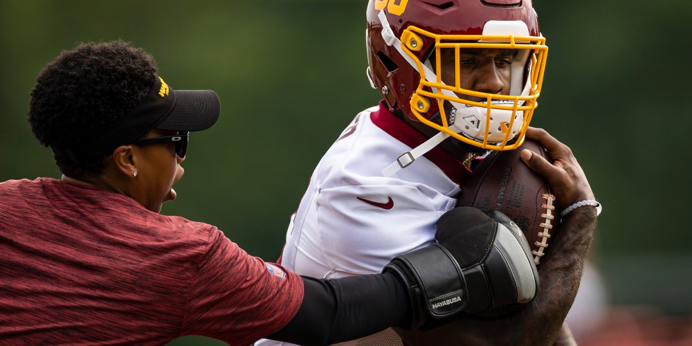 Image: Lamar Miller of the Washington Football Team participates in a drill with assistant running backs coach Jennifer King.