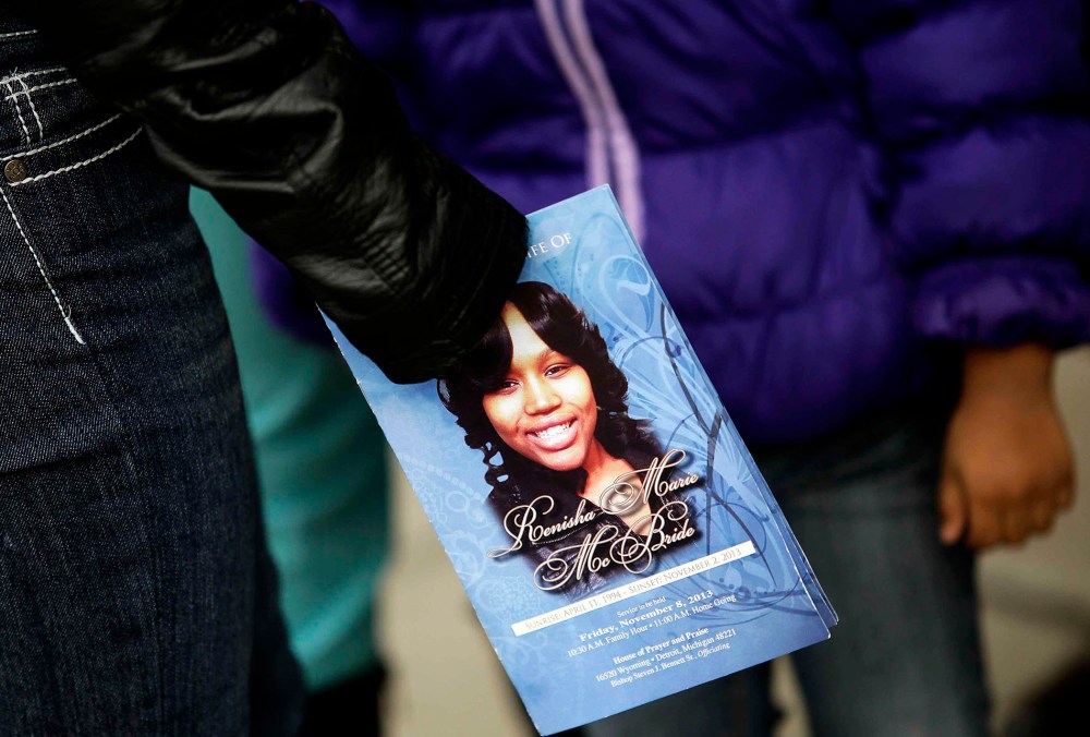 A mourner holds an obituary displaying a picture of shooting victim Renisha McBride during her funeral service in Detroit, Michigan November 8, 2013.