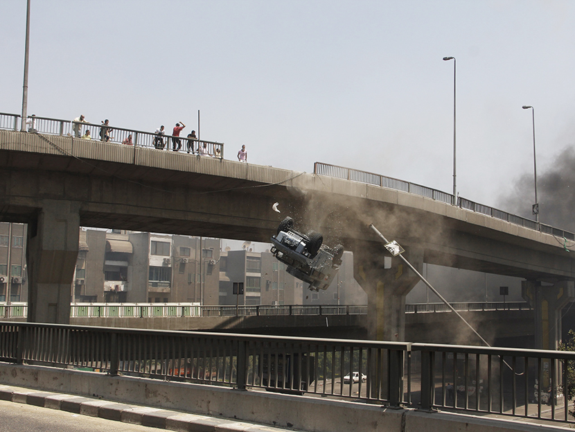 A police vehicle is pushed off of the 6th of October bridge by protesters close to the largest sit-in by supporters of ousted Islamist President Mohammed Morsi in the eastern Nasr City district of Cairo, Egypt, Wednesday, Aug. 14, 2013.  (Photo by...