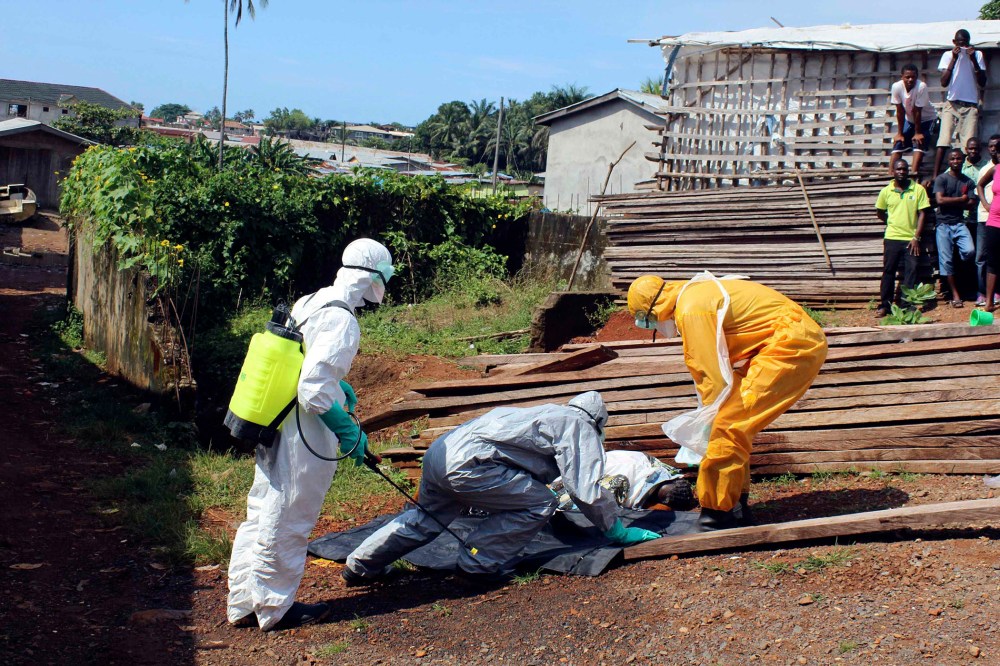 Health workers remove the body a woman who died from the Ebola virus in the Aberdeen district of Freetown, Sierra Leone on Oct. 14, 2014.