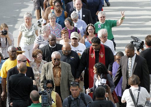 The Rev. William Barber, right center, with red sash, leads a group into the Legislative Building as the Monday protests are held at the General Assembly in Raleigh, NC on Monday, June 3, 2013. (Photo by: Chris Seward/AP Photo/The News &amp; Observer)