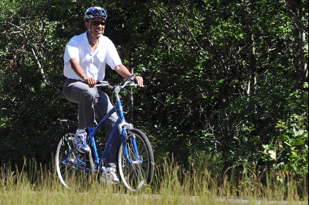 US President Barack Obama rides his bicycle in West Tisbury on Martha's Vineyard, Massachusetts, on Aug. 27, 2010.