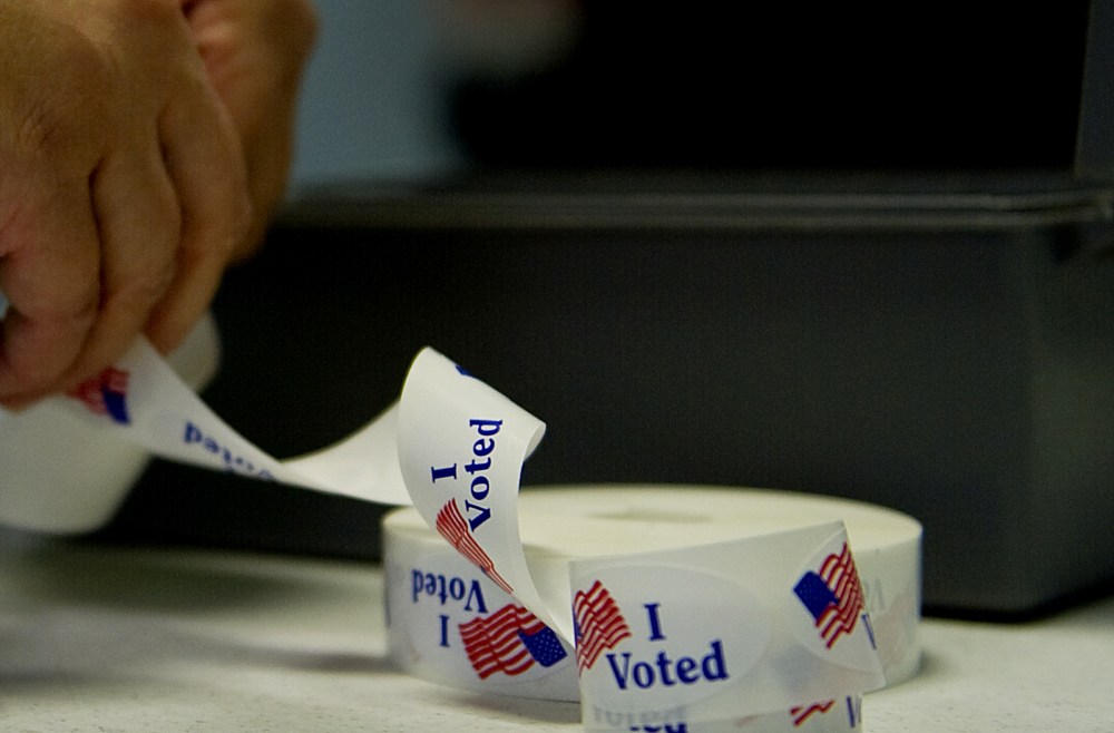 A voter peels off an "I Voted" sticker after casting her ballot at a polling station. (Photo by Jim Watson/AFP/Getty)
