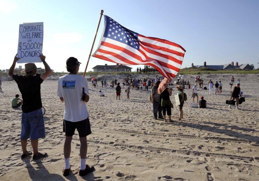 Protesters demonstrate on the beach in front of the home of industrial billionaire David H. Koch (background right) on Sunday, July 8. Romney would be among the nation's richest presidents if elected.