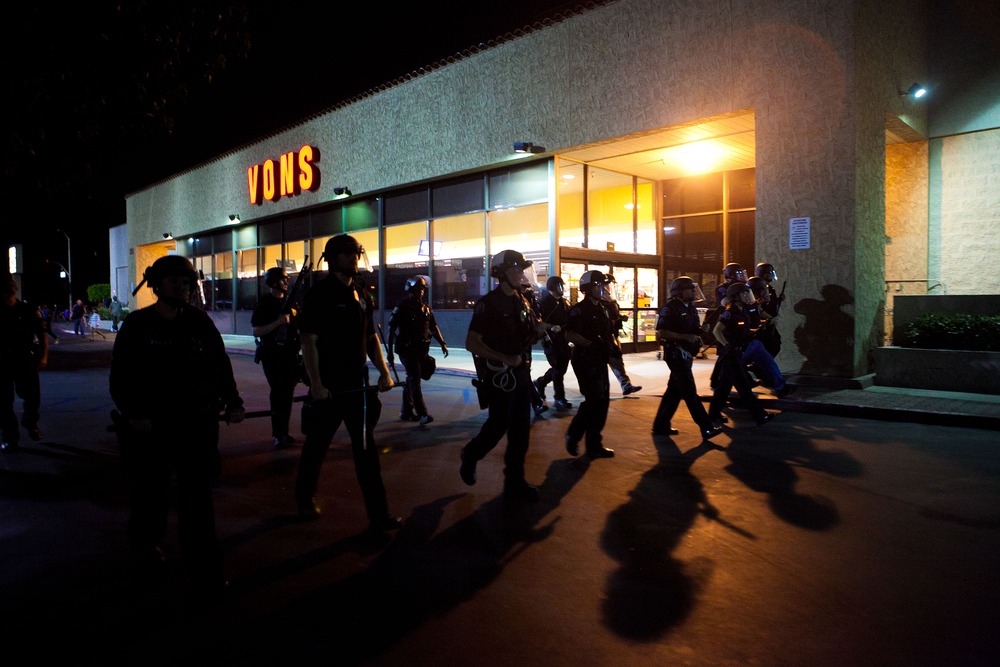 ANAHEIM, CA - JULY 24: A scrimmage line of police officers march through a shopping center after violence erupted between officers and protesters during demonstrations to show outrage for the fatal shooting of Manuel Angel Diaz, 25, at Anaheim City...