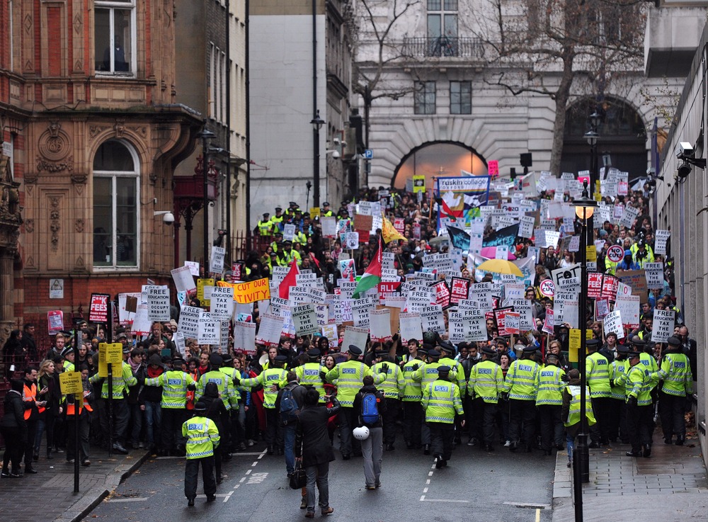 Police officers keep control during a student rally in central London on November 21, 2012 against sharp rises in university tuition fees, funding cuts and high youth unemployment. (AFP PHOTO/CARL COURT)
