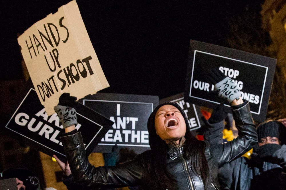 A protester, demanding justice for the death of Eric Garner, Michael Brown and Akai Gurley, shouts slogans while holding a placard as she takes part in march through Manhattan, New York on Dec. 7, 2014.