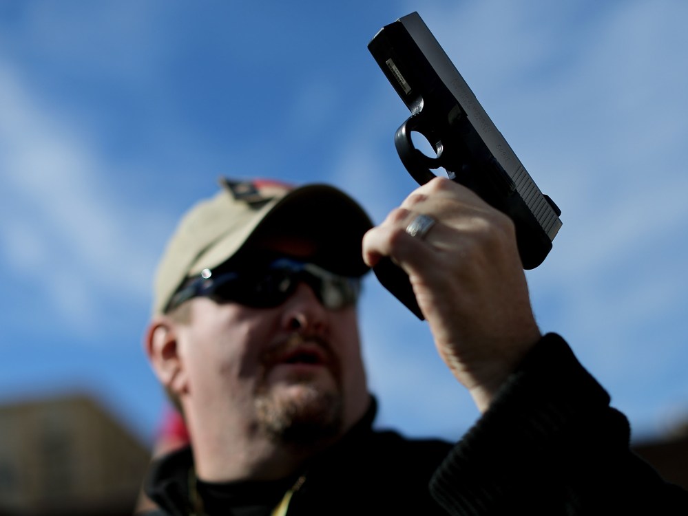 Second Amendment supporter and gun enthusiast Derek Ringley displays an unloaded pistol that was being sold in an impromptu auction across the street from a gun buy back program at the First Presbyterian Church of Dallas on January 19, 2013 in Dallas,...