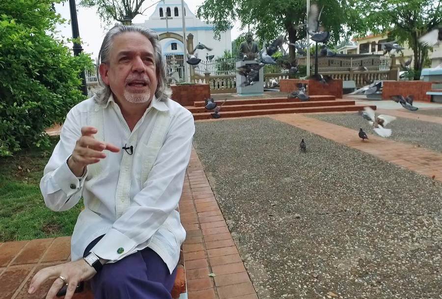Lin-Manuel Miranda's father, Luis Miranda, sits in the town square, or 