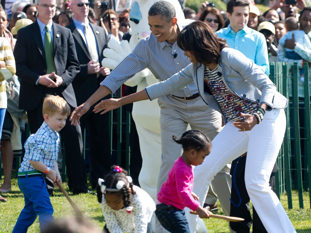 President Barack Obama  and Michelle Obama (R) cheer on children as they race to roll eggs as they participate in the White House Easter Egg Roll April 1, 2013. (Photo by Saul Loeb/AFP/Getty Images)