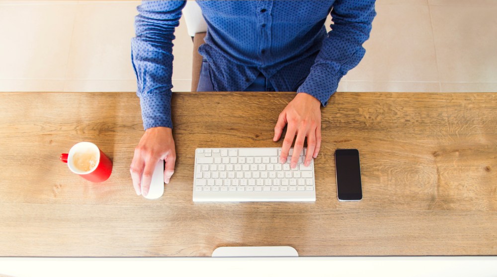 Image: A man uses a computer on a tidy desk