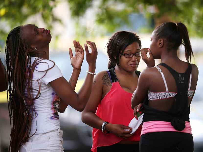 Young women watch as police prepare to remove the remains of their friend after he was shot and killed on June 22, 2013 in Chicago, Illinois. (Photo by Scott Olson/Getty Images)