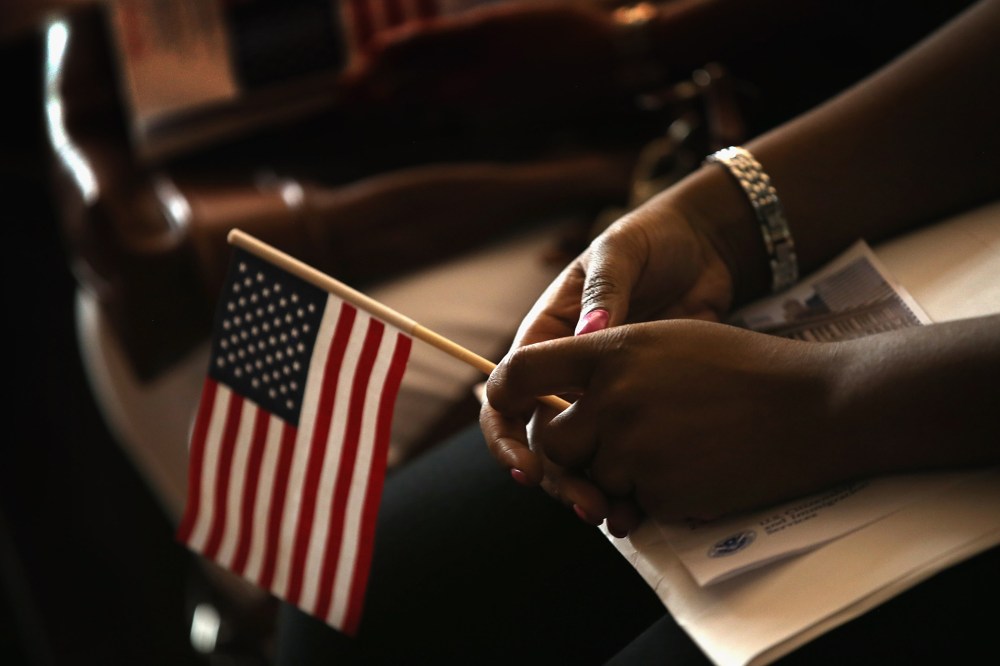 A new U.S. citizen holds an American flag along with her citizenship papers as she participates in a naturalization ceremony at the Chicago Cultural Center on July 3, 2013 in Chicago, Ill.