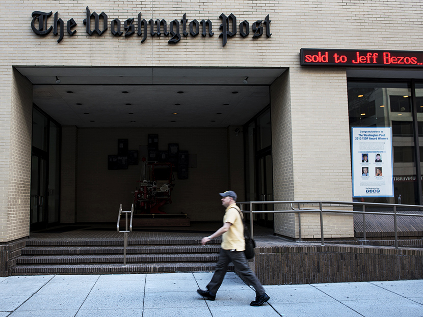 A man walks past The Washington Post building on August 5, 2013 in Washington, DC, after it was announced that Amazon.com founder and CEO Jeff Bezos had agreed to purchase the Post for USD 250 million. (Photo by Brendan Smialowski/AFP/Getty)