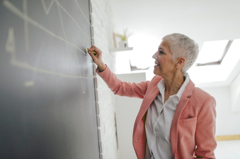 Businesswoman Drawing Chart On Blackboard In Her Office.
