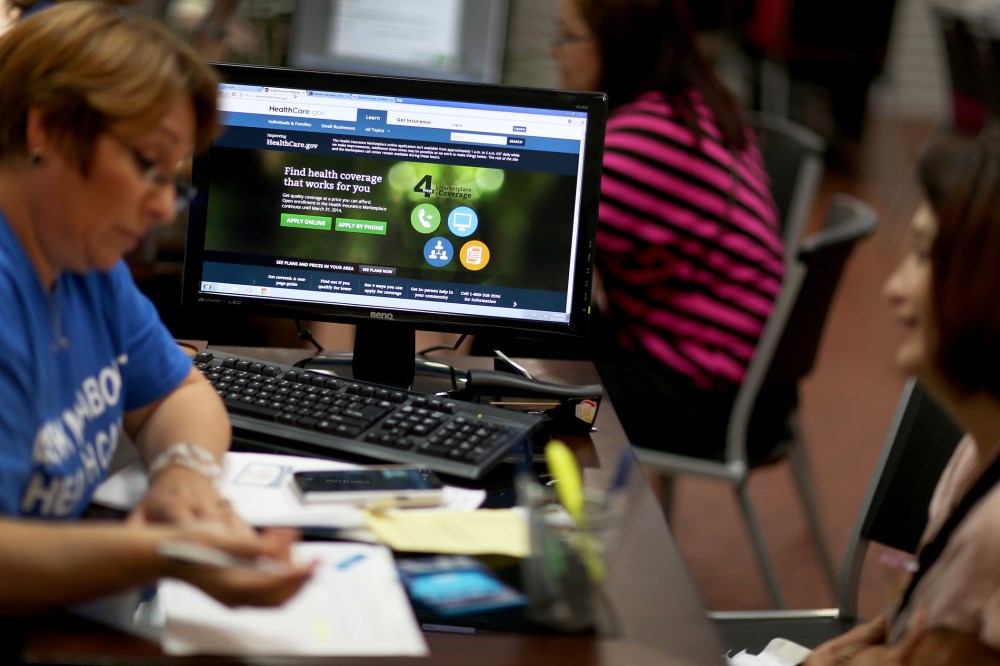 An insurance agent helps a woman purchase an insurance policy under the Affordable Care Act at the store setup in the Westland Mall on Nov. 14, 2013 in Hialeah, Fla. (Photo by Joe Raedle/Getty)