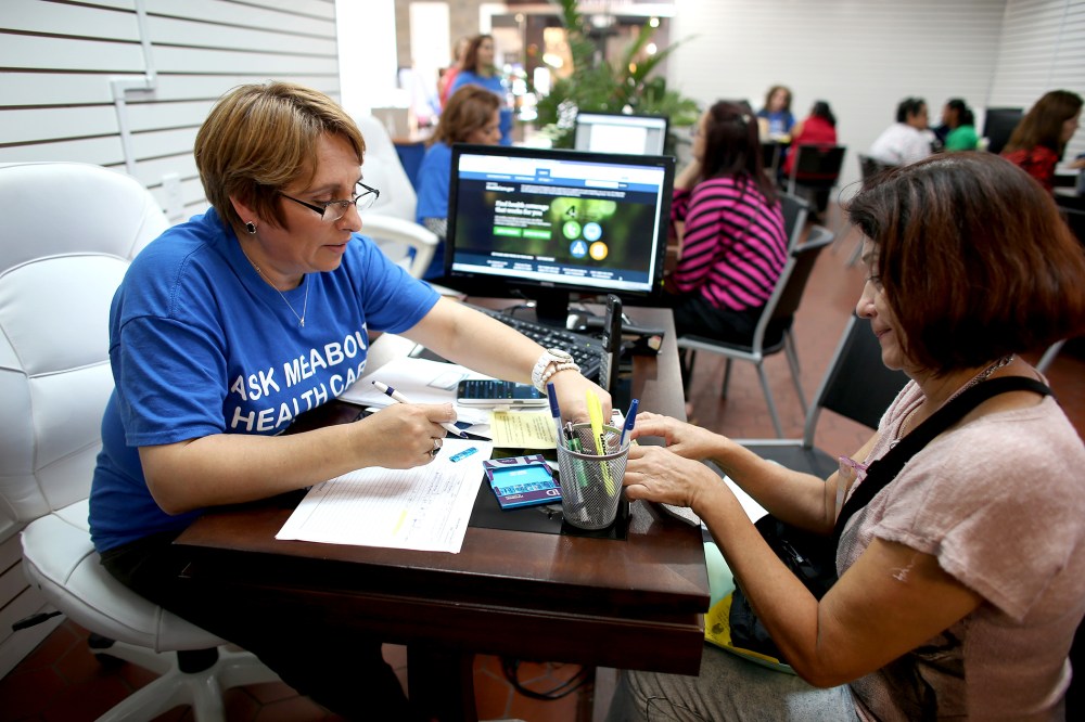 Mercy Cabrera (L), an insurance agent with Sunshine Life and Health Advisors, helps Amparo Gonzalez purchase an insurance policy under the Affordable Care Act at the store setup in the Westland Mall on Nov. 14, 2013 in Hialeah, Fla.