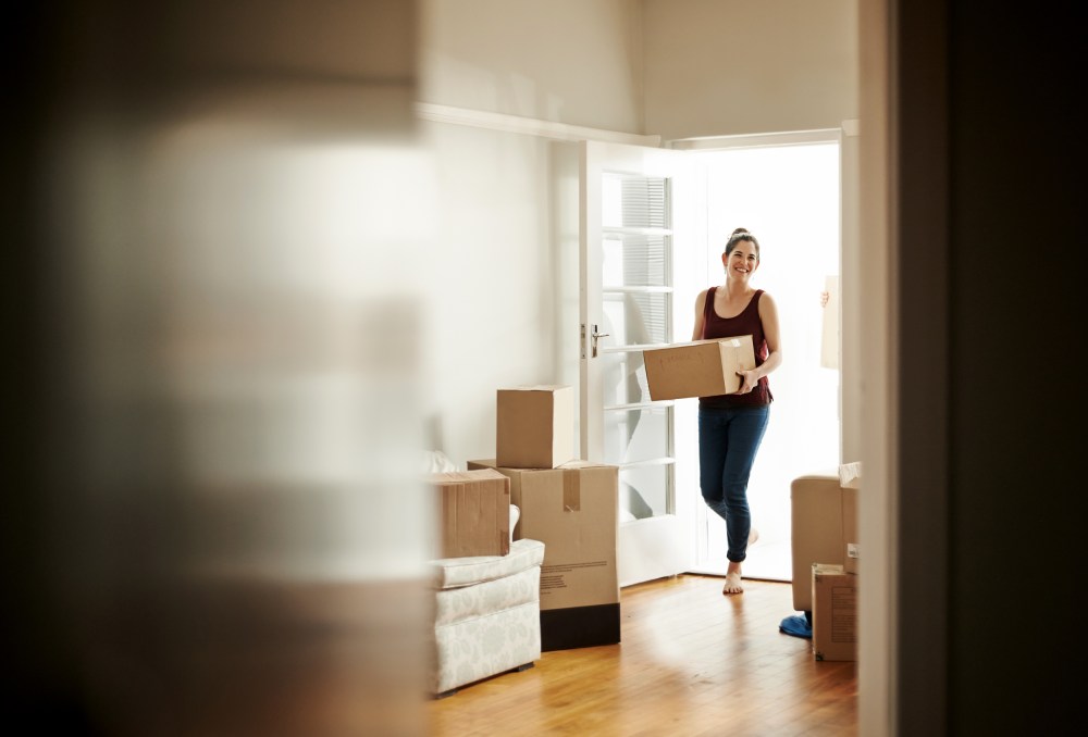 Image: Woman carrying boxes into her new home.