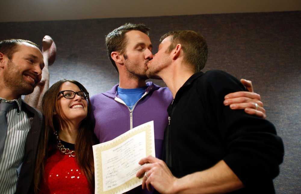 The first gay couple to be married in Utah, Michael Ferguson (2nd R) and his husband Seth Anderson (R), kiss as Blake Ferguson (L) and his girlfriend Danielle Morgan watch after the pair married at the Salt Lake County Clerks office in Salt Lake City, Uta