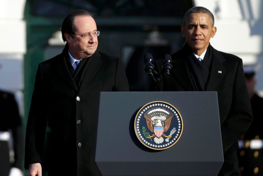 French President Francois Hollande (L)  looks over at U.S. President Barack Obama during a State Arrival ceremony in Hollande's honor on the South Lawn of the White House in Washington, February 11, 2014.