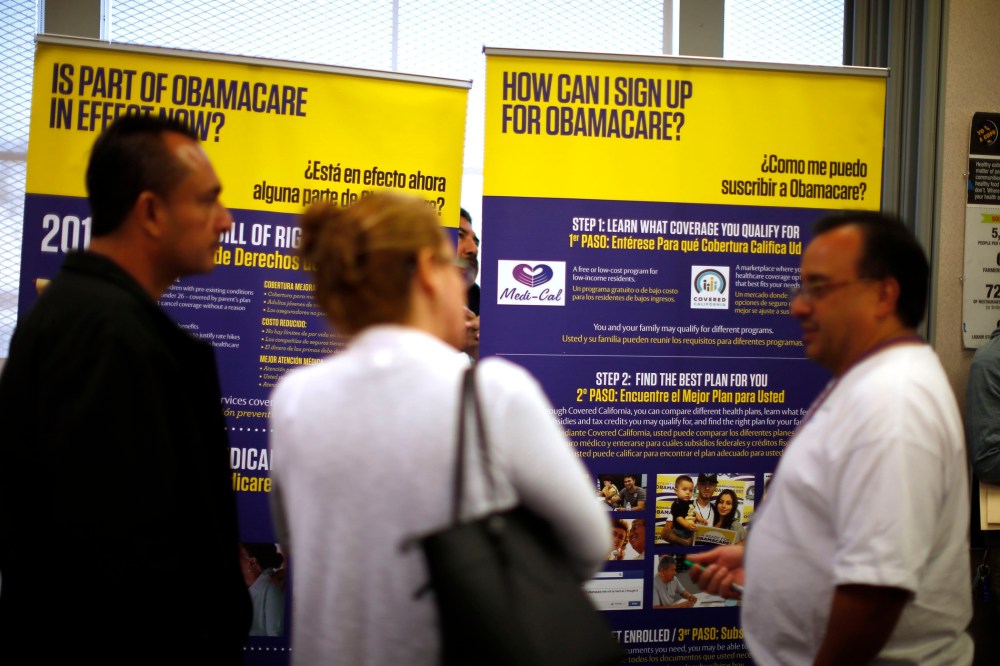 Julian Gomez (R) explains Obamacare to people at a health insurance enrollment event in Commerce, California March 31, 2014.