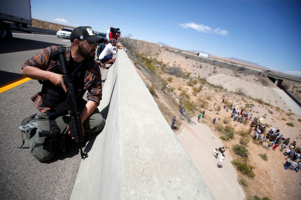 Eric Parker from central Idaho stands watch on a bridge with his weapon as protesters gather by the Bureau of Land Management's base camp, where cattle that were seized from rancher Cliven Bundy are being held, near Bunkerville, Nevada, April 12, 2014.