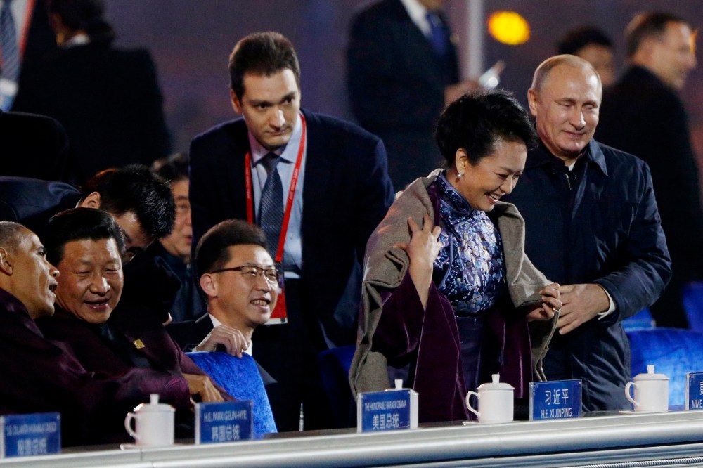 Russia's President Vladimir Putin (R) helps put a blanket on Peng Liyuan (2nd R), wife of China's President Xi Jinping (2nd L), as Xi talks to U.S. President Barack Obama (L) during a lights and fireworks show to celebrate Asia-Pacific Economic Cooperatio