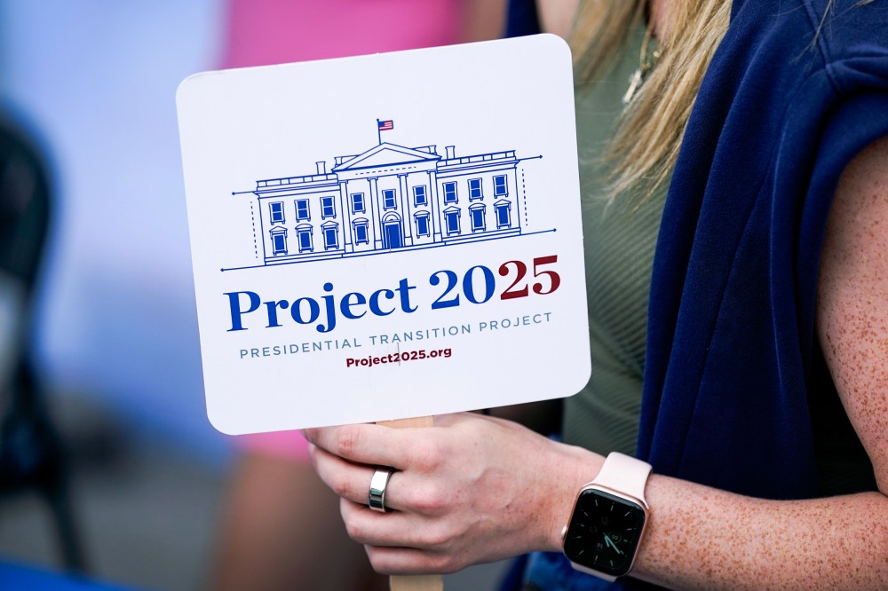 A fairgoer holds a Project 2025 fan at the Iowa State Fair in 2023.