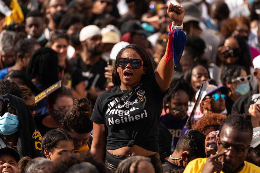 A woman raises her fist in the air prior to the arrival of Vice President Kamala Harris at the 57th anniversary of 