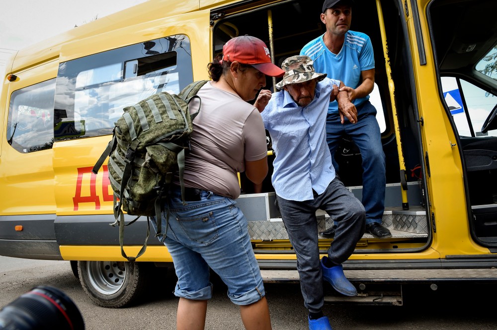 People help evacuate an elderly man from an area near the site of explosion at an ammunition storage of Russian army near the village of Mayskoye in Crimea on Tuesday.