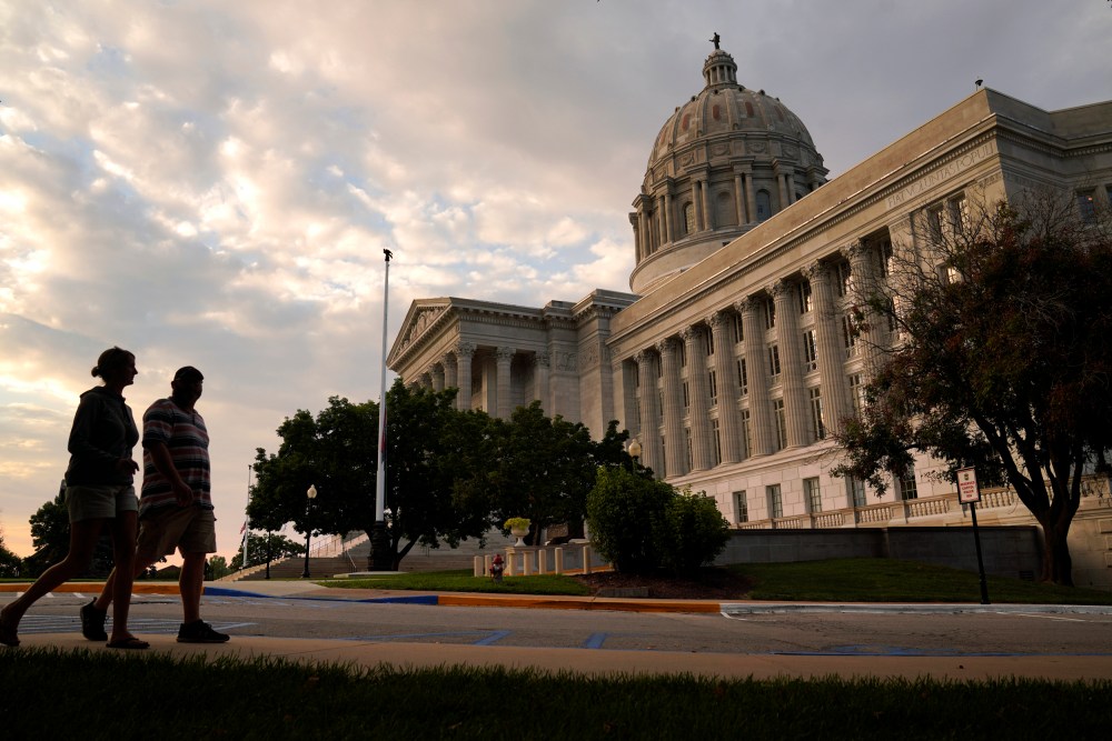 People walk past the Missouri State Capitol in Jefferson City, Mo.