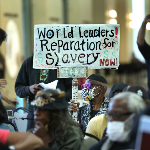 Walter Foster holds up a sign as the Reparations Task Force meets to hear public input on reparations in Los Angeles